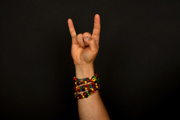 Hand with devil horns and colorful beads isolated on black